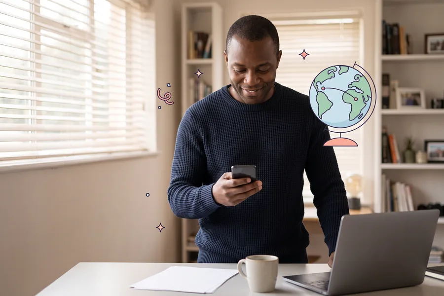 Man in a home office in the morning with his phone, a small globe beside him