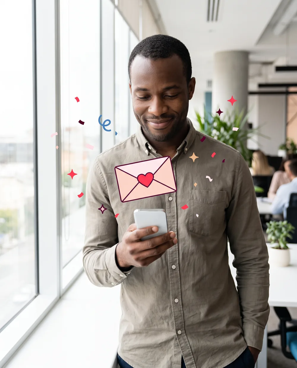 Man by an office window smiling as he reads a kind note on his phone